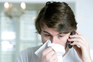 Man blowing his nose on the phone